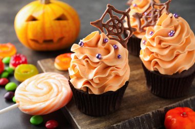 Çikolata ağlı enfes kekler, gri masaya serpiştirilmiş şekerler, yakın plan. Cadılar Bayramı