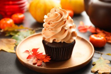 Lezzetli kek ve sonbahar yaprakları gri masada, yakın plan.