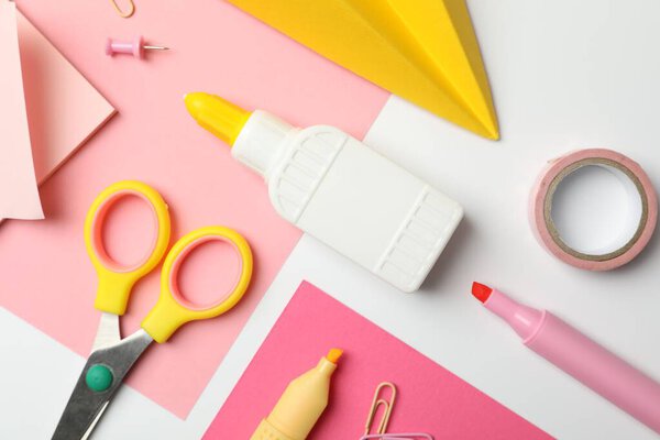 Glue and other stationery on white background, flat lay