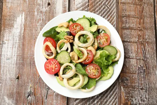 Ahtapot yüzüklü lezzetli salata, avokado, fındık ve sebzeler ahşap masada, üst manzara