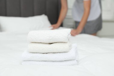Otel odasında çalışan oda hizmetçisi, yataktaki havlu yığınına odaklan.