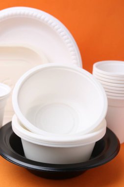 Turuncu arkaplanda tek kullanımlık plastik sofra takımı, yakın plan.