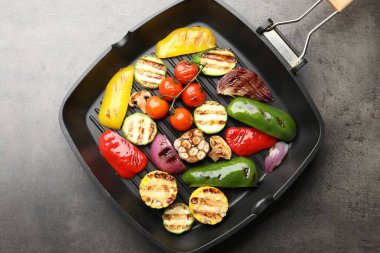 Gri masada ızgara sebze ve baharatlı tava, üst manzara.