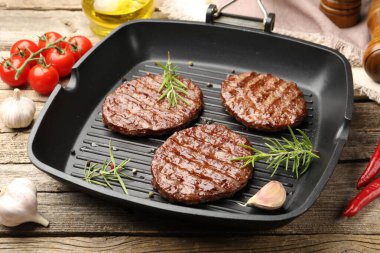 Izgara köfteli tava, domates ve baharatlar ahşap masada, yakın plan.