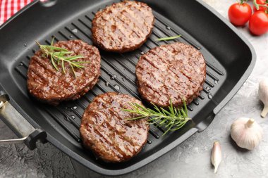 Izgara köfteli tava, domates ve baharatlar gri masada, yakın plan.