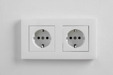 Beyaz duvarda elektrik prizleri var.