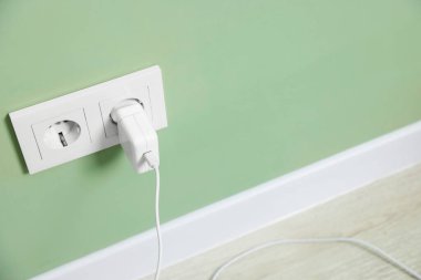 Yeşil duvardaki elektrik prizine bağlı USB adaptörü, metin için boşluk