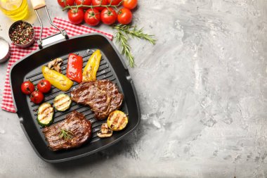 Izgara biftek, mantar, sebze ve baharatlı tava. Gri desenli masa, düz yatak. Metin için boşluk