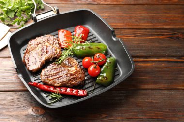 Izgara biftekli tava, biberiye ve sebzeler ahşap masada, yakın plan. Metin için boşluk