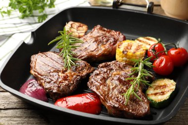 Tavada ızgara biftek, biberiye ve sebzeler ahşap masada, yakın plan.