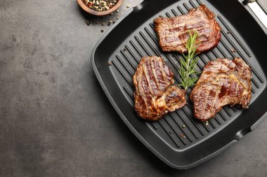 Izgara biftekli tava, biberiye ve biberiyeli, gri desenli masa, düz yatak. Metin için boşluk