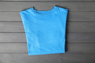 Light blue t-shirt on grey wooden table, top view. Mockup for design