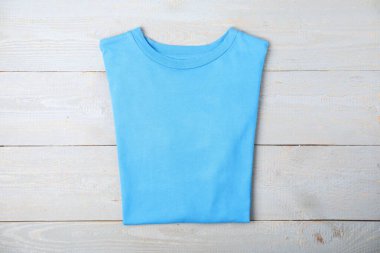 Light blue t-shirt on wooden table, top view. Mockup for design