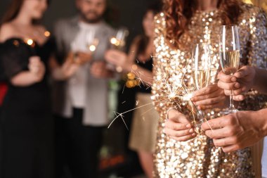 Yeni yılı evde maytap ve şarap kadehleriyle kutlayan arkadaşlar, yakın plan.