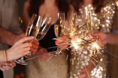 Yeni yılı evde maytap ve şarap kadehleriyle kutlayan arkadaşlar, yakın plan.
