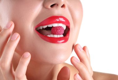 Dudaklarında güzel kırmızı ruj ve beyaz arka planda ahududu şekeri olan kadın, yakın plan.