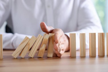 Risk. Tahta masada domino efektini durduran adam, yakın plan.