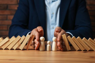 Risk. Tahta masada insan figürlerini domino etkisinden koruyan adam, yakın plan.