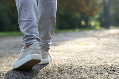 Havalı spor ayakkabılı bir adam asfaltta yürüyor, yakın plan. Metin için boşluk
