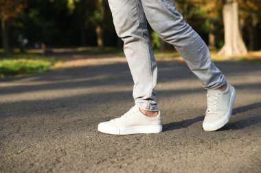 Havalı spor ayakkabılı bir adam asfaltta yürüyor, yakın plan. Metin için boşluk
