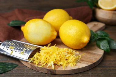 Limon, taze meyve, rende ve yeşil yapraklar ahşap masada, yakın plan.