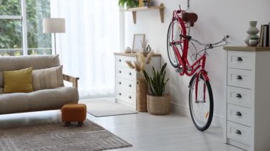 Kırmızı bisiklet, kanepe ve oda çiçekleri, sola hareket eden kamera.