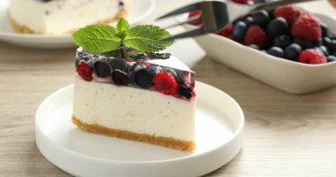 Lezzetli peynirli kek yiyen bir kadın ve beyaz ahşap masada nane şekeri, yakın plan.