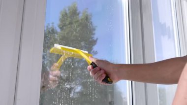 Pencereyi temizleyen adam. Kapalı mekanda, düşük açılı. Kamera hareket ediyor