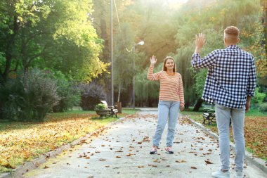 Bir adam parktaki arkadaşına el sallıyor.