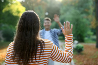 Bir adam parkta arkadaşına el sallıyor, seçici odaklanma.