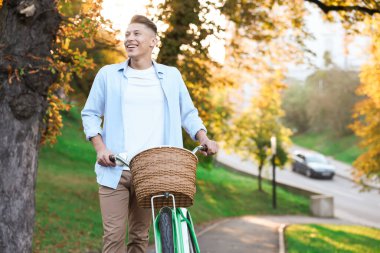 Güneşli bir günde parkta bisikletini gezdiren mutlu bir adam. Metin için boşluk