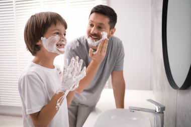 Baba oğul banyoda yüzlerine tıraş köpüğü sürüyorlar.