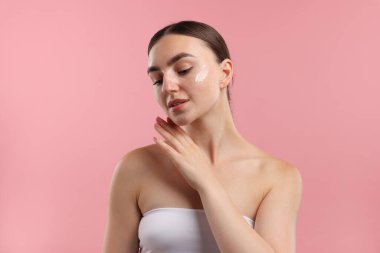 Pembe arka planda krem sürmüş güzel bir kadın.