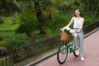 Dışarıdaki sepetin içinde çiçeklerle bisikletini gezdiren bir kadın. Metin için boşluk