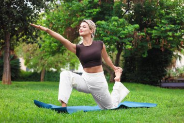 Parkta yoga yapan genç bir kadın.