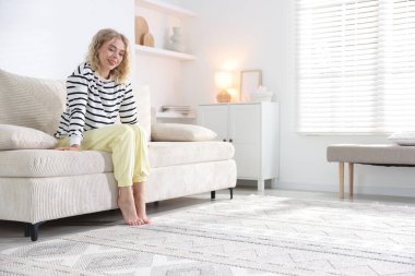 Evdeki kanepede dinlenen mutlu genç kadın, mesaj için yer.