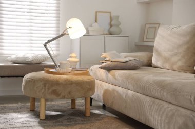 Şık lamba, vazo, kitaplar ve fincanlar kapalı koltuğun yanında.