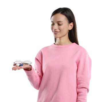 Beyaz arkaplanda gözlük ve kontak lens arasında seçim yapan kadın