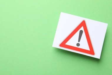 Risk. Sheet of paper with warning sign on green background, top view and space for text