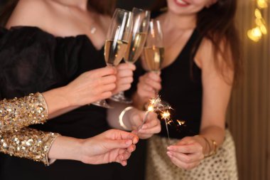 Yeni yılı evde maytap ve şarap kadehleriyle kutlayan kadınlar, yakın plan.
