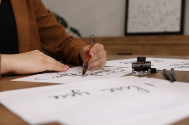 Kaligrafi. Fırça darbeleriyle yazı yazan kadın Tahta masadaki kağıda teşekkür ederim