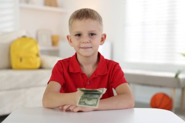Beyaz masada cep harçlığı tutan küçük çocuk.