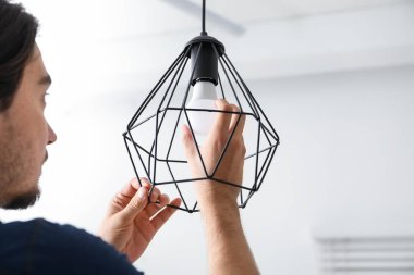 İçerideki şık lambada ampulü değiştiren adam.