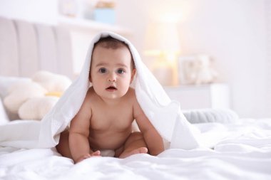 Evdeki yatakta banyo yaptıktan sonra beyaz havluyla sarılı şirin bir bebek. Mesaj atmak için yer var.