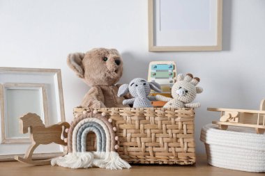 Beyaz duvarın yanındaki ahşap masada farklı oyuncaklar ve dekorlar.