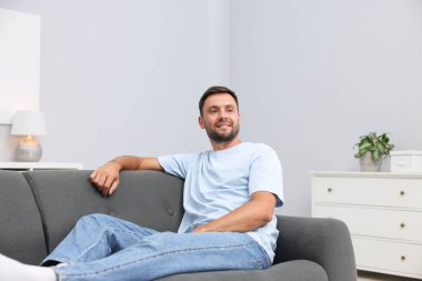 Evdeki kanepede dinlenen mutlu adam.