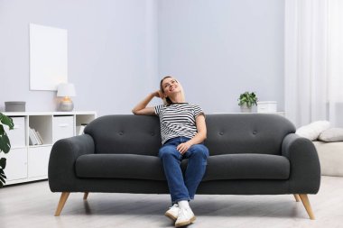 Evdeki kanepede dinlenen mutlu kadın.
