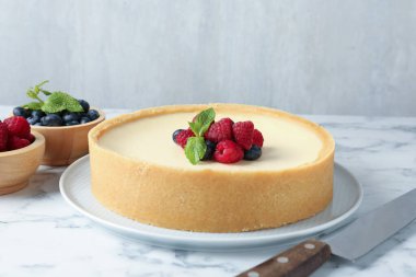 Taze böğürtlenli leziz cheesecake ve beyaz mermer masada bıçak, yakın plan.