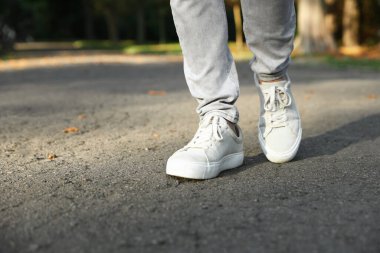 Havalı spor ayakkabılı bir adam asfaltta yürüyor, yakın plan. Metin için boşluk