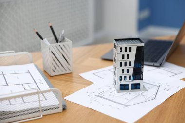 Gayrimenkul. Apartman modeli, mimari çizimler ve dizüstü bilgisayar kapalı masa, yakın plan.